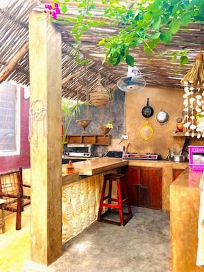A kitchen with a bar area, a hanging basket, and a wall-mounted clock.