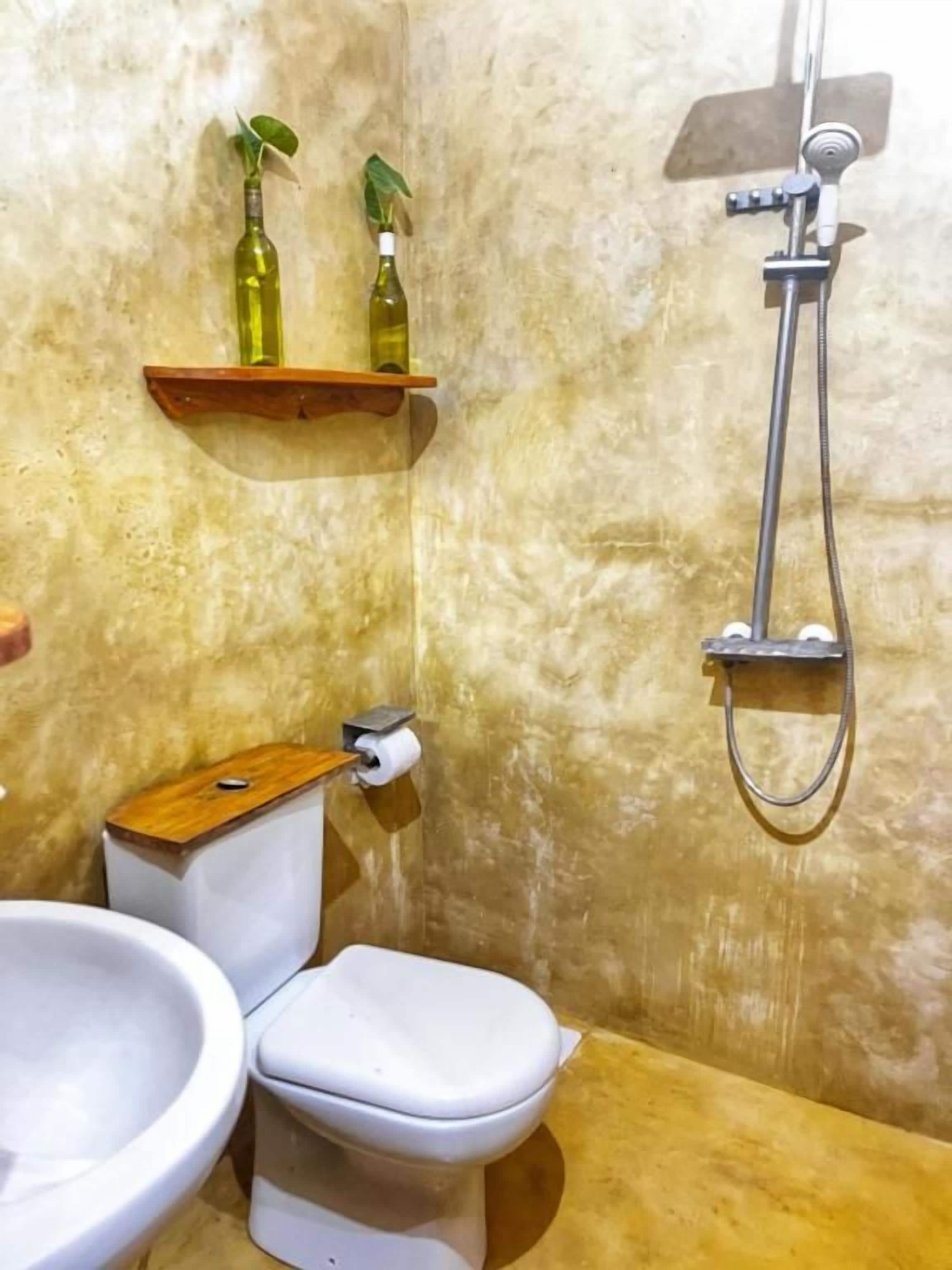 Un baño con inodoro, bidé, ducha y dos botellas en un estante.