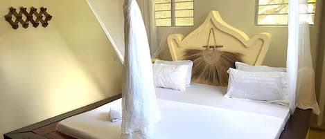 A bed with a canopy, a headboard with a decorative element, and a wall-mounted light fixture.