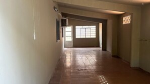 A long hallway with tiled flooring, a ceiling fan, and a window with a grid pattern. - House in the Center of Corumbá - Heart of the Pantanal (Corumbá)