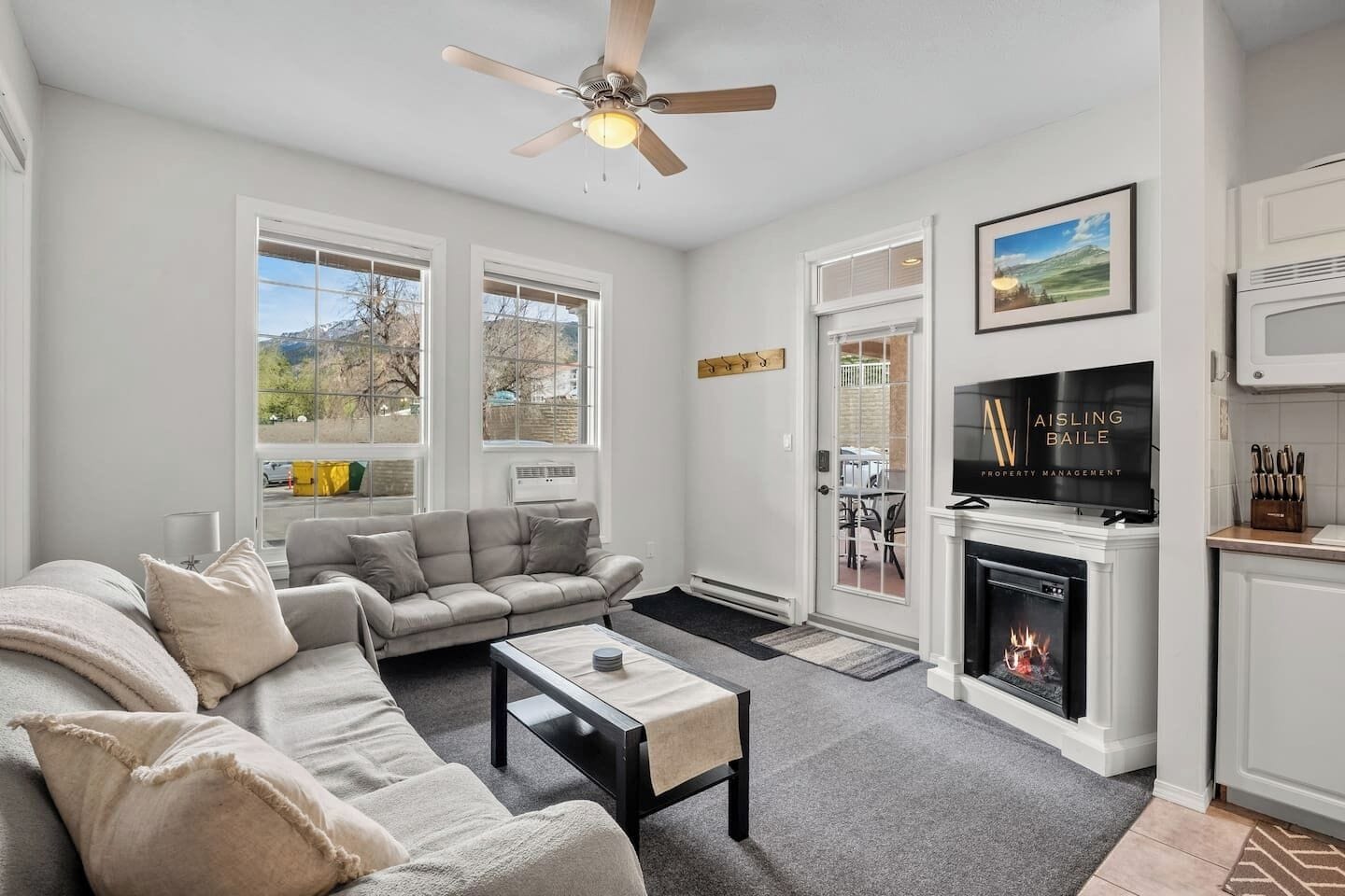 Living room with an electric fireplace, Smart TV, walkout access to the ground-floor patio, and cozy seating options with a double-sized sleeper sofa (all linens provided.)