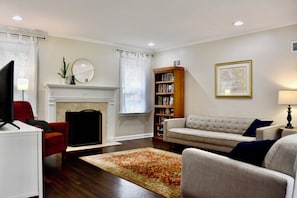 A living room with a fireplace, a sofa, a bookshelf, and a television.