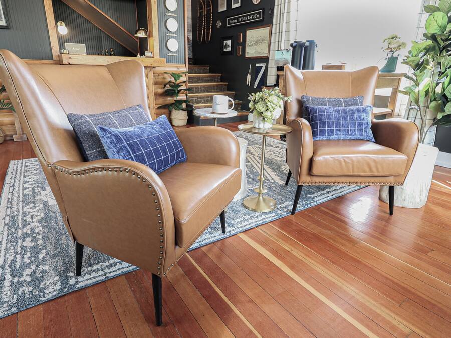 A room with two leather armchairs, a small round table, a coffee table, and a large potted plant.
