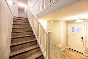 Eine Holztreppe mit weißen Geländern, die zu einer Zwischenebene führt.