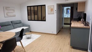 Een moderne leefruimte met een bank, eettafel en keukenhoek.