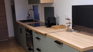Een moderne keuken met grijze kastjes, een houten aanrechtblad en een bordje met de tekst 'Welcome'.