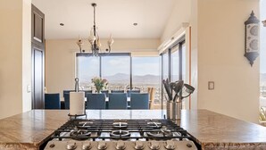 A kitchen with a gas stove, a chandelier, and a view of the city through large windows.