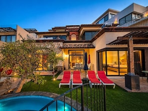 A modern house with a swimming pool, red lounge chairs, and a well-maintained garden. - Villa Corazon de Fatima 4BR + Panoramic-Views (Cabo San Lucas)