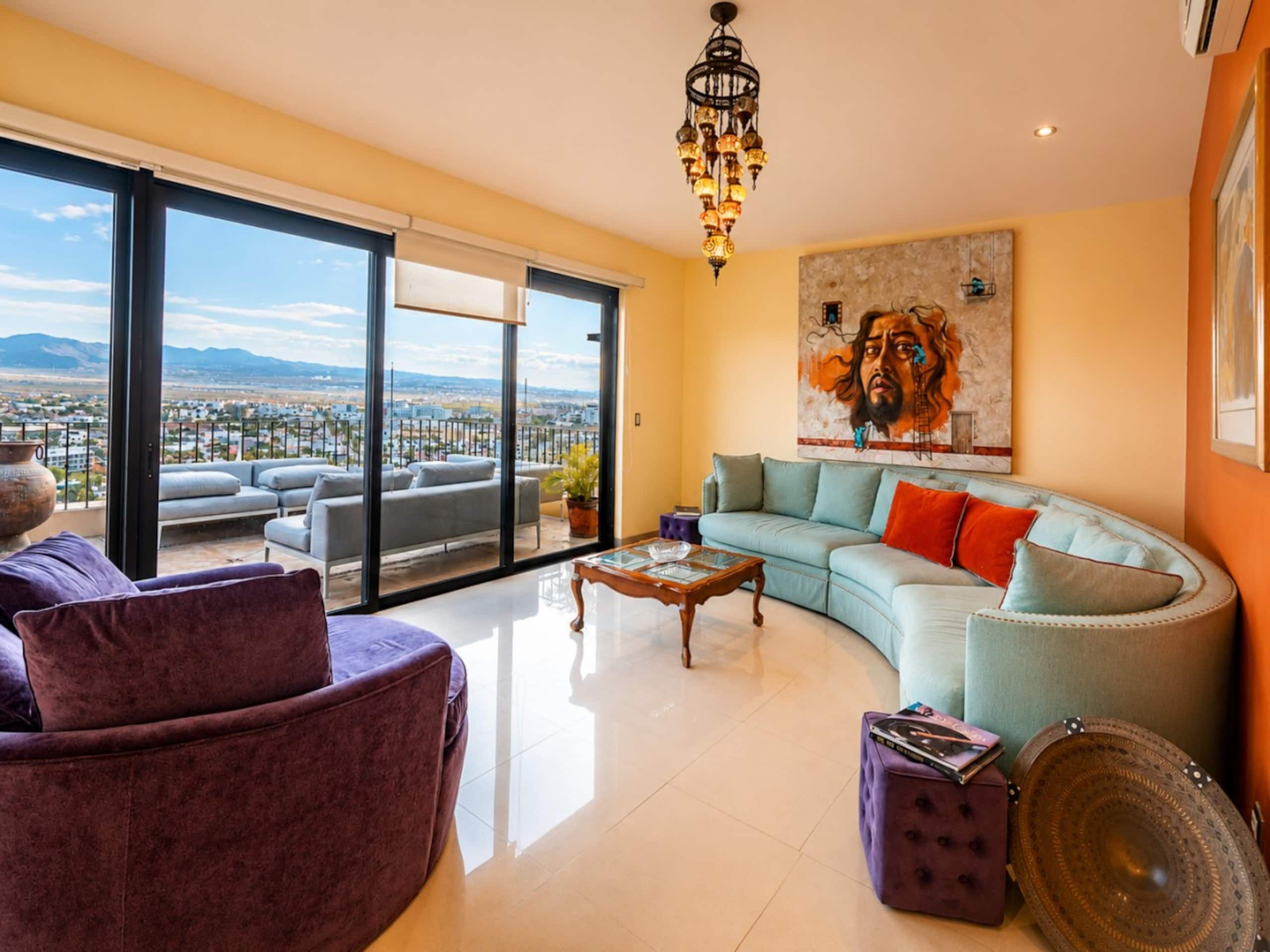 A spacious living room with a large window, a sofa, a coffee table, and a decorative plate.