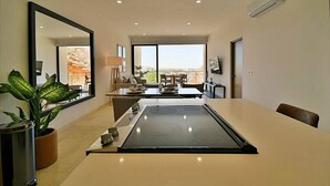A modern kitchen with a central island, a dining area with a view, and a large mirror. - Ocean View-Heated Pool-Walk everywhere in Cabo (Cabo San Lucas)