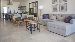 A modern living room with a sofa, chairs, a coffee table, and artwork on the wall. - Ocean View-Heated Pool-Walk everywhere in Cabo (Cabo San Lucas)