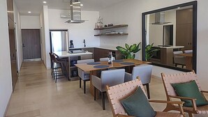 A modern kitchen with built-in appliances, a dining area with a wooden table and chairs, and a large mirror on the wall. - Ocean View-Heated Pool-Walk everywhere in Cabo (Cabo San Lucas)