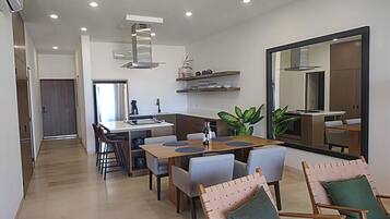 A modern kitchen with built-in appliances, a dining area with a wooden table and chairs, and a large mirror on the wall.