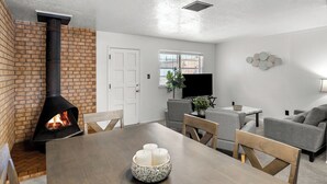 A modern living room with a fireplace, a dining table with candles, and a gray sofa.