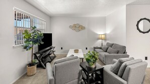 A modern living room with grey sofas, a coffee table, a TV, and a lamp.