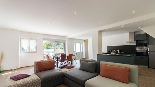 A modern living room with a sofa, a dining area with chairs, and a kitchen with appliances. - Pareine - BEAUTEVILLE (BEAUTEVILLE)