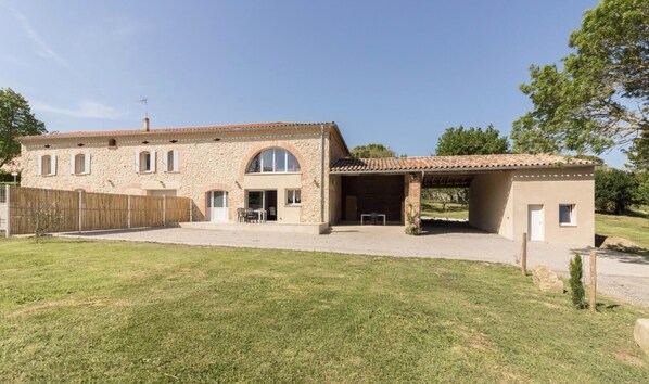 Una casa de piedra de dos pisos con un porche cubierto y un patio cercado.