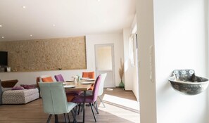 Un comedor moderno con una mesa de madera, sillas coloridas y un cuadro abstracto grande en la pared.