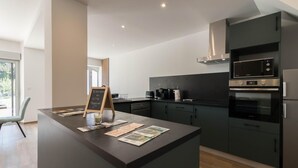 A modern kitchen with dark cabinetry, a central island, a microwave, and an oven. - Pareine - BEAUTEVILLE (BEAUTEVILLE)