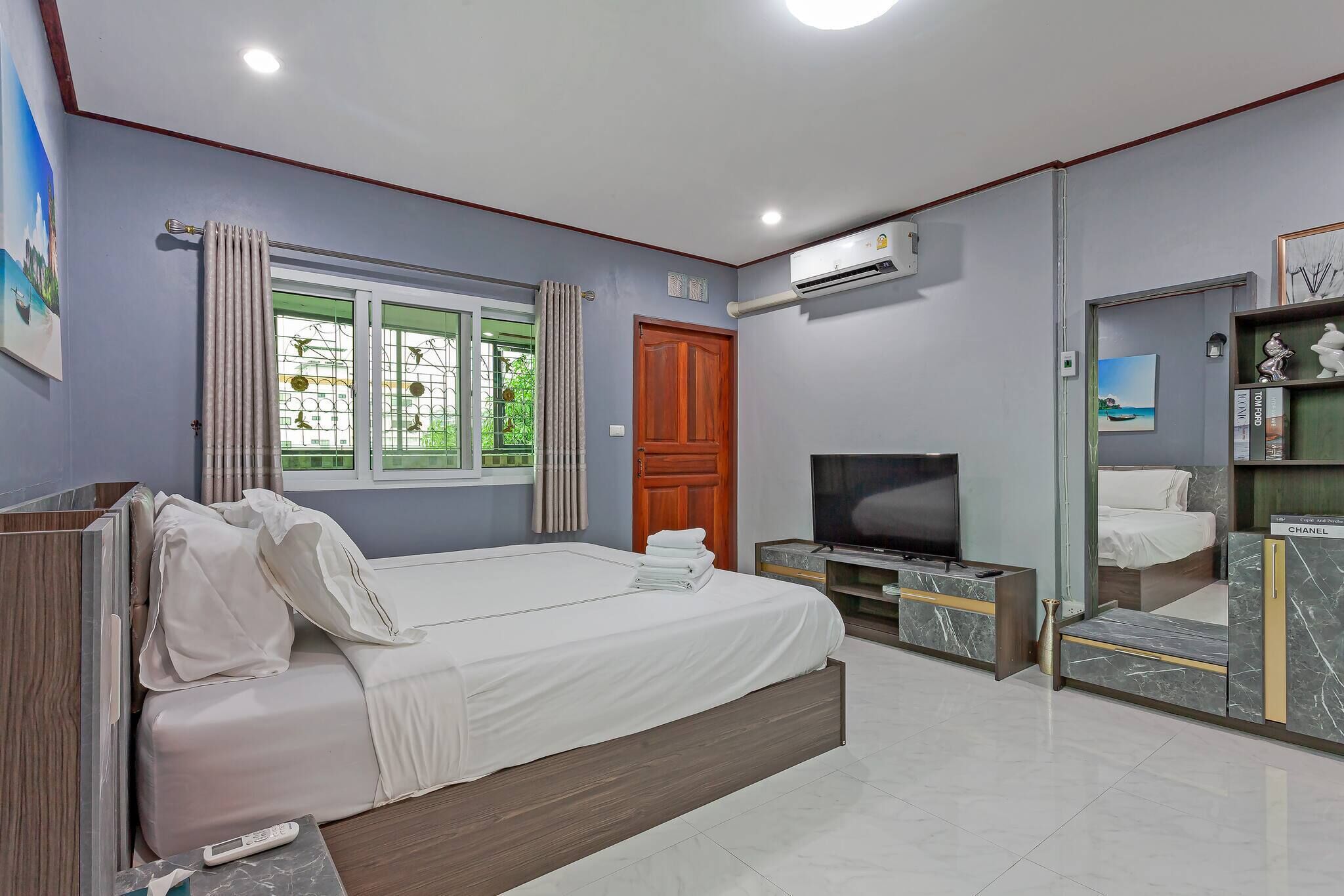Une chambre à coucher comprenant un lit, une télévision, un appareil de climatisation et une armoire.