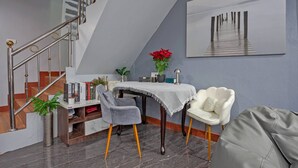Ein modernes Interieur mit einer Treppe, einer Essecke mit Tisch und Stühlen sowie einem großen gerahmten Kunstwerk an der Wand.