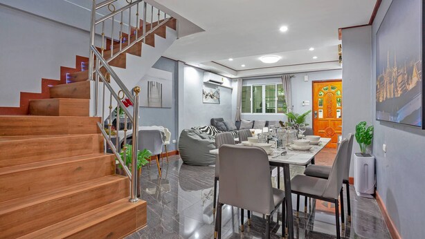 Ein modernes Interieur mit einer Holztreppe, einem Essbereich und einem Wohnzimmer mit einer Couch und einem Fernseher.