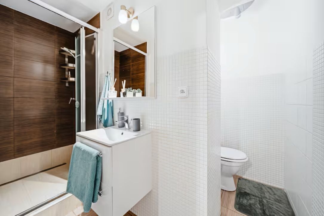 A modern bathroom with a shower, toilet, and sink.