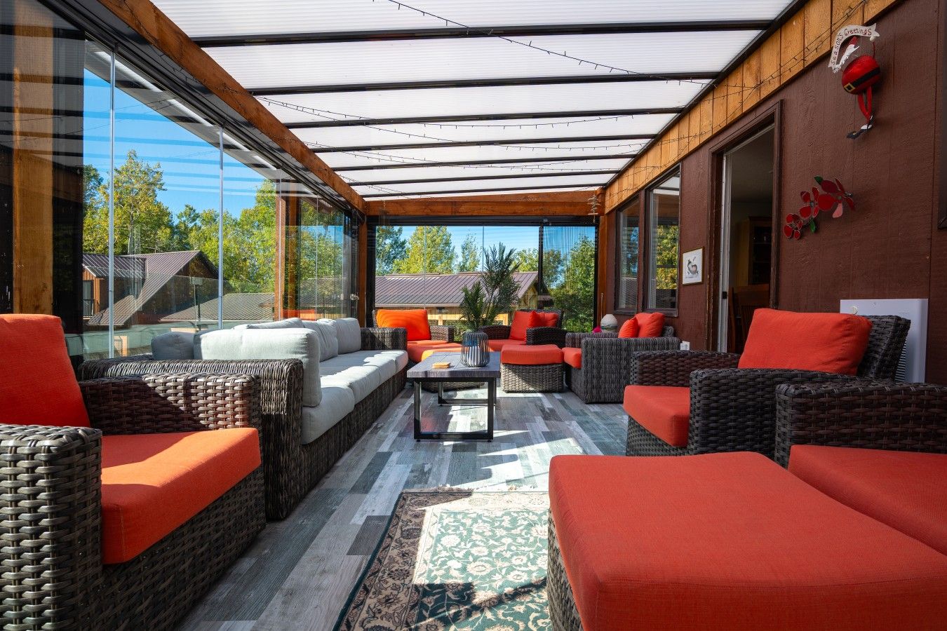 A modern outdoor seating area with wicker furniture and a glass enclosure.