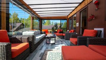 A modern outdoor seating area with wicker furniture and a glass enclosure.