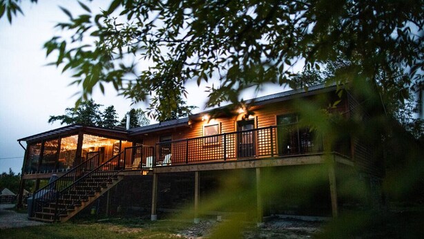 Et træhus med en overdækket veranda og en trappe op til en terrasse.
