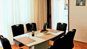 A dining area with a table set for four, chairs, a bottle of wine, and a pineapple. - Seaview Family Apartment With Grand Terrace (Omis)