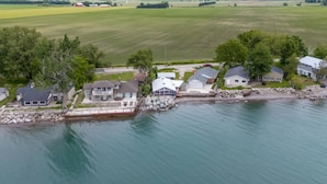 A waterfront property with houses, a dock, and a grassy field.