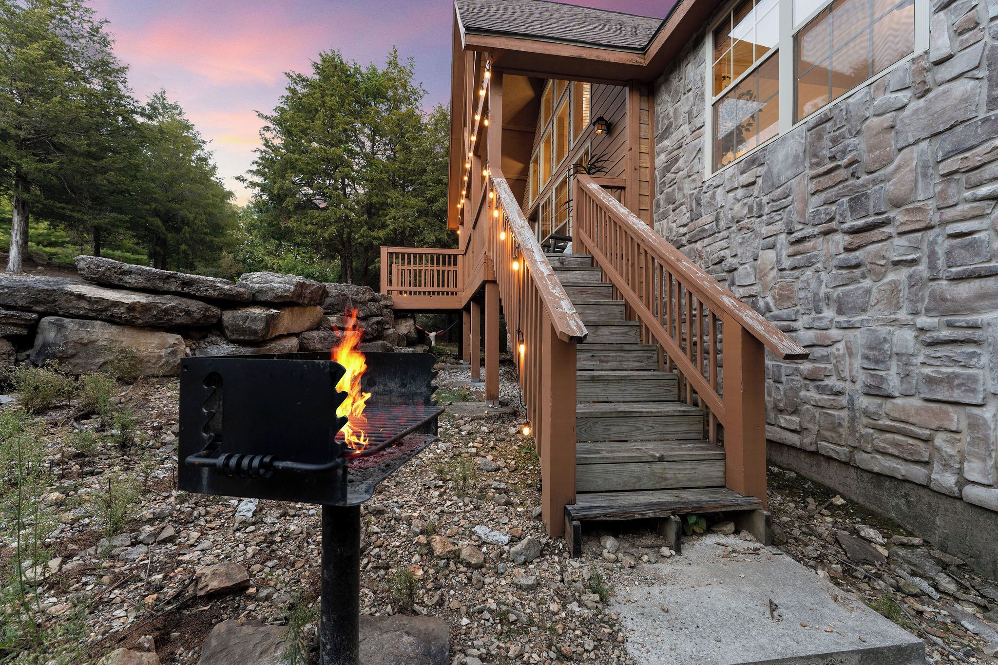 Ein Steinhaus mit einer Holztreppe und einem Grill.