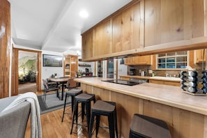 Una cocina moderna con armarios de madera, una isla central con taburetes y vistas a un comedor.