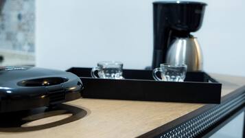 A coffee machine, two glasses, and a tray on a wooden surface.
