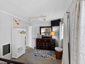 A bedroom with a bed, dresser, mirror, and a small rug.