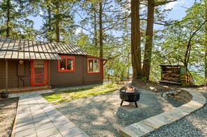 Eine Holzhütte mit roter Tür, einem Feuerkorb und einem Lager für Brennholz.