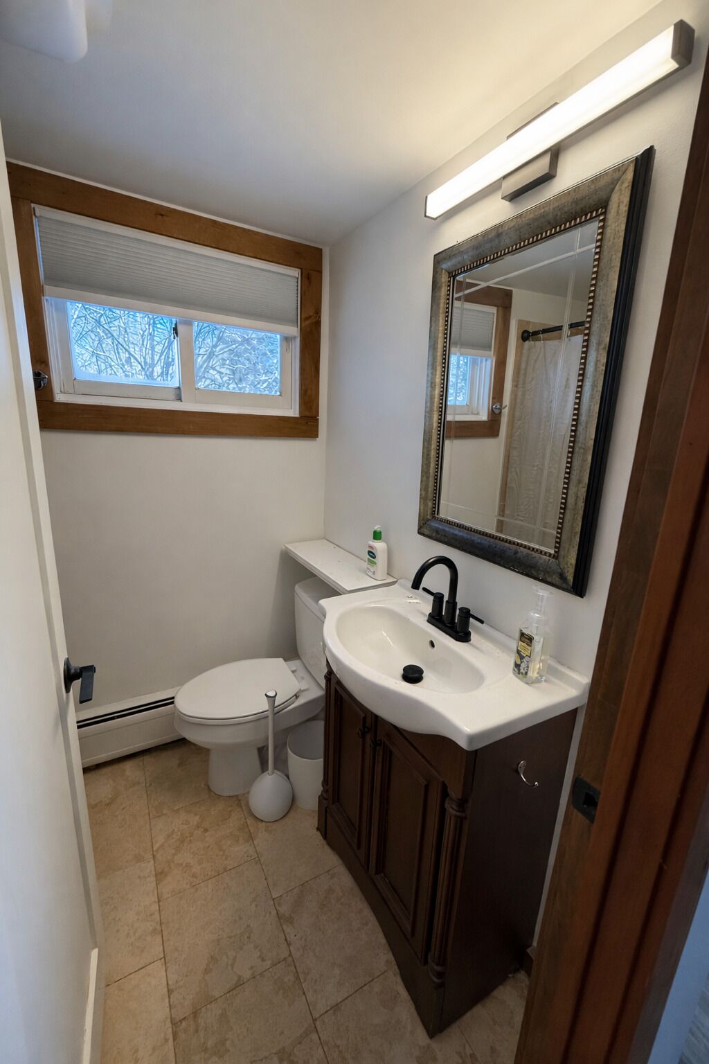 Un baño con inodoro, lavabo, espejo y ventana.