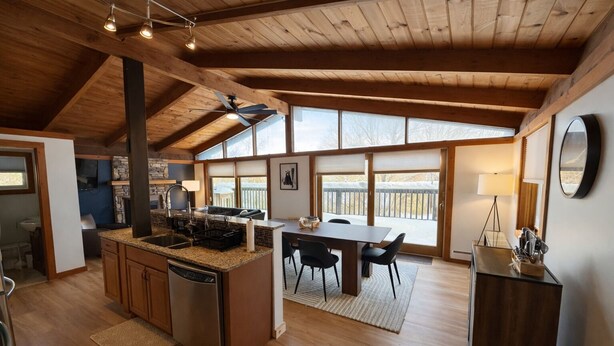 Una cocina amplia con una isla central, techo de madera y ventanas grandes.