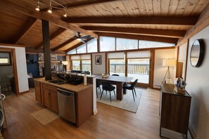 Een ruime keuken met een centraal eiland, houten plafond en grote ramen.