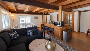 Un salón moderno con un sofá, una mesa de centro y una cocina equipada con microondas.