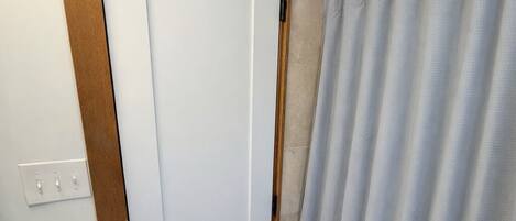 Casa de banho com lavatório branco, uma porta e cortina de chuveiro.