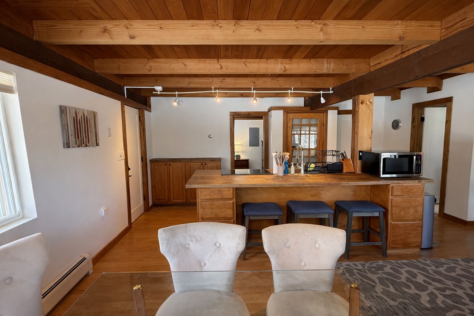 A modern kitchen with wooden beams, a bar area, and bar stools.