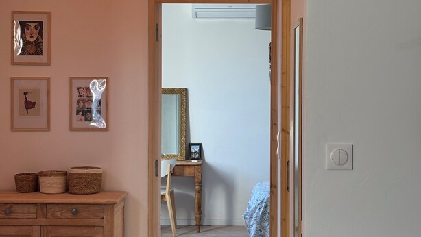 Ein Zimmer mit Holzschrank, Schreibtisch, Stuhl, Spiegel und einem Bett.