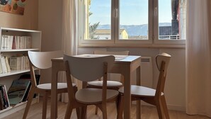 Ein Essbereich mit Tisch und Stühlen, einem Bücherregal und einem großen Fenster mit Aussicht.