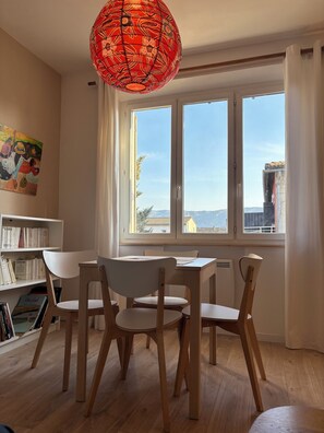 Ein Essbereich mit Tisch und Stühlen, einem Bücherregal und einem großen Fenster mit Aussicht.