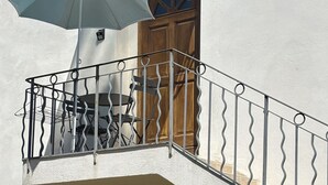 Ein Balkon mit Metallgeländer, einem Tisch und einem Stuhl.