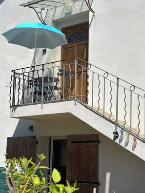 Ein Balkon mit Metallgeländer, einem Tisch und einem Stuhl.