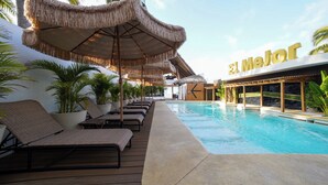 A poolside area with lounge chairs, thatched umbrellas, and a sign reading 'El Majot'. - Hotel El Mejor (San Patricio Melaque)