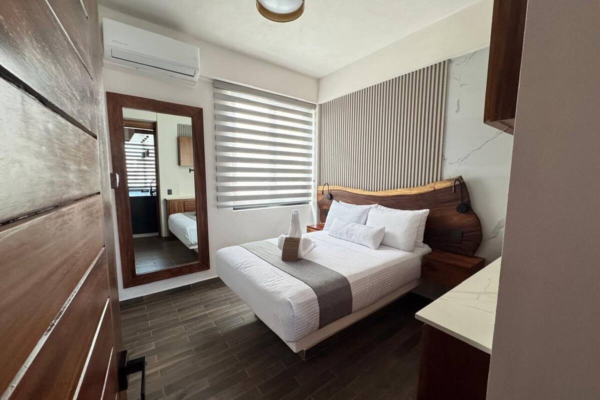 Quarto com cama, mesa de cabeceira e espelho.